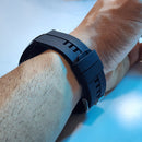 SmartWatch F22U with a sleek matte black silicone strap, featuring a ridged design and silver metallic pin buckle, worn on a wrist. Real product photo.