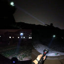 Powerful black rechargeable flashlight shown in 4 real night usage photos. Its intense beam highlights distant hills, buildings, and close-up terrain. Features a textured body, large head, and red button.