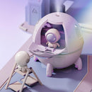3D render: Cute pastel pink/lavender spaceship humidifier with a subtle gradient, emitting mist. Its front opens to reveal a tiny white astronaut figure. Another astronaut stands outside in a minimalist, light purple setting. Smooth plastic design.