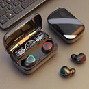 Glossy black M10 Bluetooth earbuds with red and blue accents. The open power bank charging case features a digital display showing "100%", "Be Loud Be Proud", and battery icons. Another identical case is closed. Real product photo on a dark, textured surface.