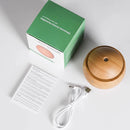 Spherical wood-grain aroma diffuser & humidifier, alongside its green box labeled 'Ultrasonic Aroma Humidifier with Color Changing LED', a white USB cable, and instructions, all on a white surface. Real product photo.