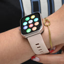 Smartwatch NX22 on a wrist: square AMOLED screen displaying colorful apps, rose gold-toned case, and light pink silicone band with holes. A gold braided bracelet is also visible. Real image, ideal for GPS and calls.