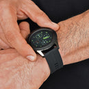 A man's wrist displays a SmartWatch F22U, featuring a round black metal case and a textured black silicone strap. Its digital screen shows vibrant green health metrics. "Smart Watch" is subtly engraved on the side. Real image.