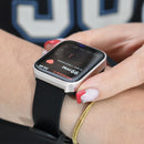 Real image of an NX22 Smartwatch with a silver metal frame & black silicone band on a wrist. The AMOLED screen displays "99 PPM" heart rate, "Frecuencia C...", and "04:49".