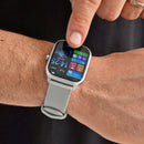 Real image: KT65 Pro smartwatch with a silver frame & light grey silicone band worn on a wrist. A finger touches the rectangular color screen displaying time (14:25), date, steps, heart rate, calories, & 20°C.