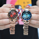 Two women's rose gold watches held by hands. Left: red dial, round crystal, diamond markers & sub-dial. Right: blue dial, faceted diamond-cut crystal, diamond markers, "QUARTZ". Real photo.