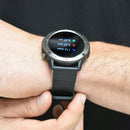 SmartWatch NX9 on a wrist: dark gray bezel, black ribbed silicone strap. Its round Amoled screen shows fitness data (116 Steps, 3.67 Kcal, 0.07 Km). Real photo, sporty design.