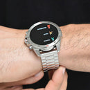 NX1 Pro smartwatch on a wrist, with a sleek silver metal band & round bezel. The black display shows 'Montañismo,' 'Correr,' 'Caminar' (mountaineering, run, walk) activity options & icons. Elegant real product image.
