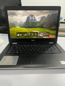 Open used DELL Inspiron 3493 laptop on white desk. Features black keyboard, carbon fiber texture, and a screen showing a vibrant green mountain landscape, time 3:57. Visible DELL and Intel Core i3 branding. Real photo.